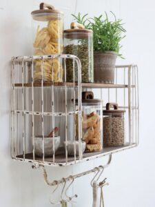 rustiikkinen hyllykkö asennettu seinälle, jossa ovat keittiön lasipurkit ja kukka ruukussa