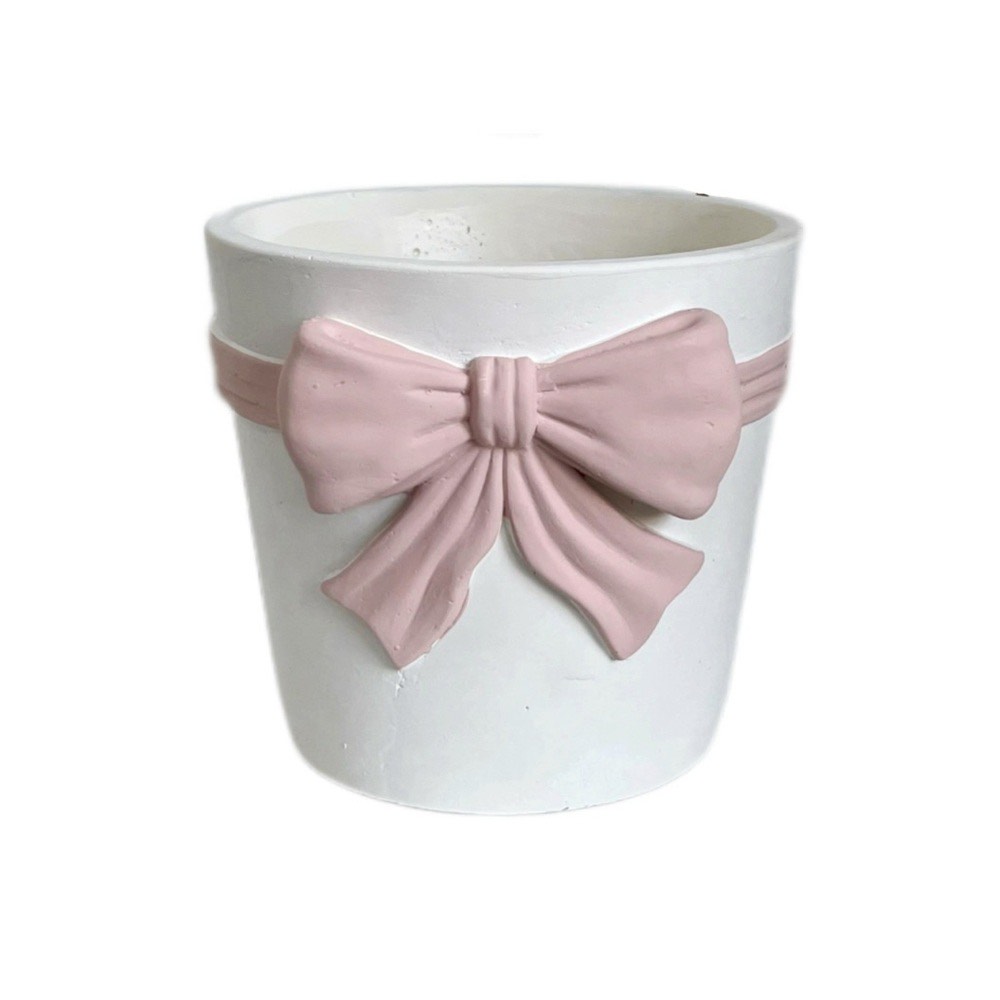 keraaminen kukkaruukku kohokuvioitu rusetilla pöydällä