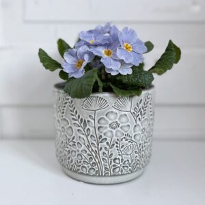 kukkaruukku harmaassa värissä kukalla seisoo pöydällä