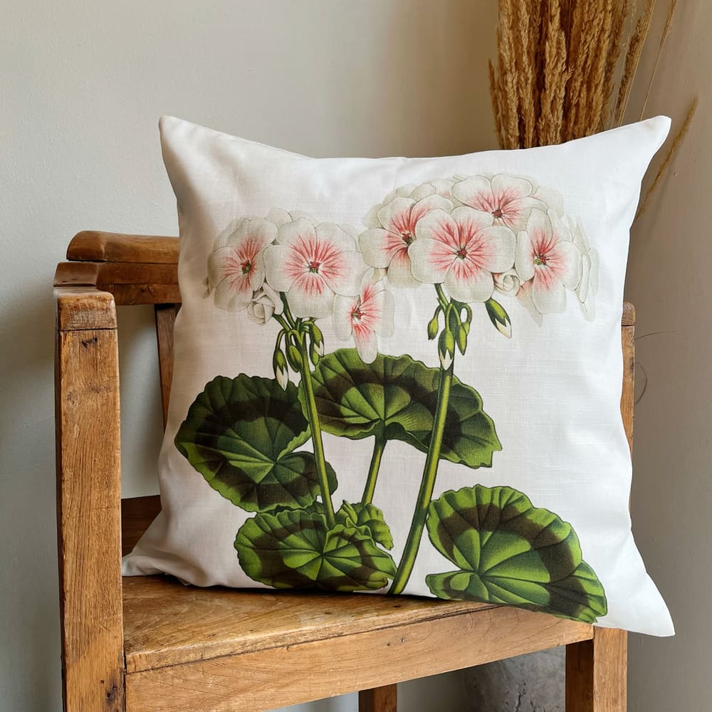 tyynynpällinen puuvilla jossa pelargoni kuvalla on puutuolilla